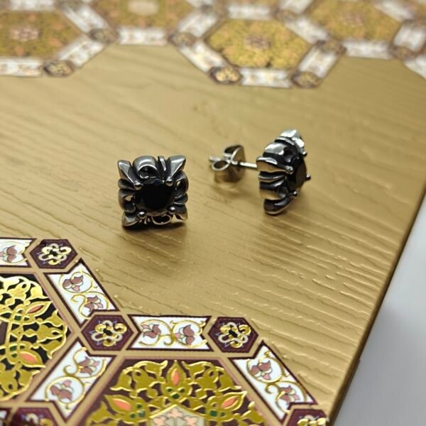“Black stone stainless steel stud earrings with gothic-style design on rustic wood background”