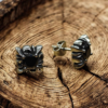 “Black stone stainless steel stud earrings with gothic-style design on rustic wood background”