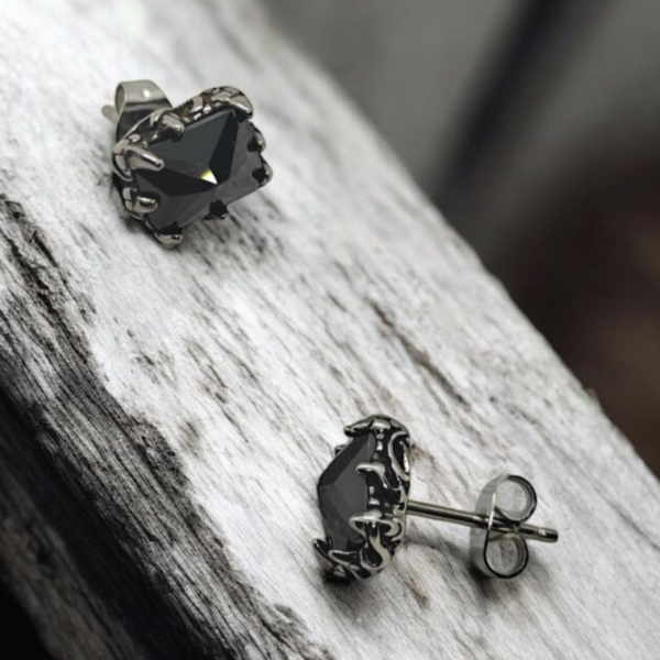 “Black stone stainless steel stud earrings on textured wood background”