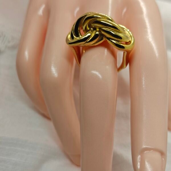 “A gold-plated stainless steel knot ring displayed on a mannequin hand over a white fabric background.”