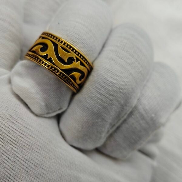 Gold plated stainless steel tribal pattern ring on white fabric
