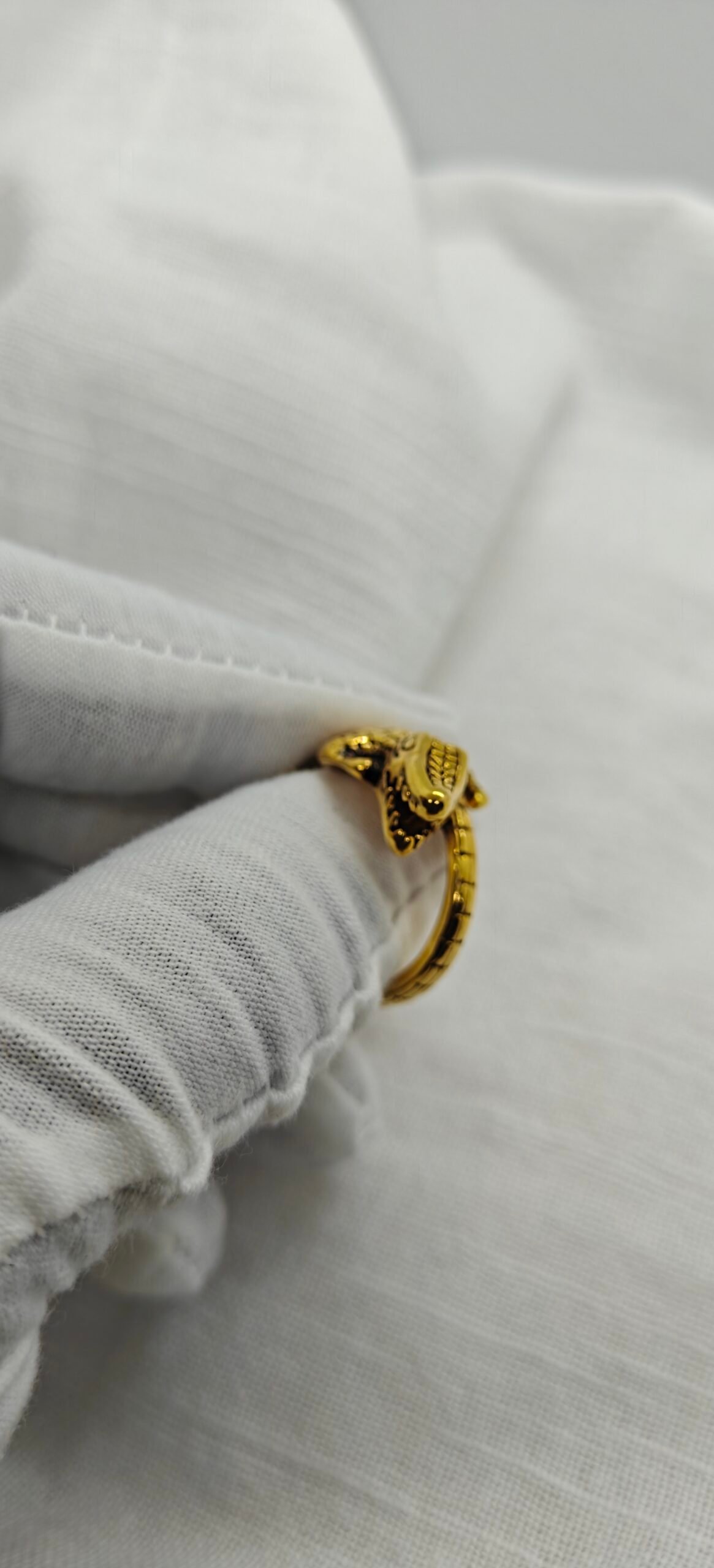 gold plated alligator ring 316l stainless steel on white fabric background