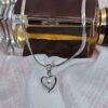 “Stainless steel heart pendant necklace with pearl center displayed on a white cloth backdrop.”