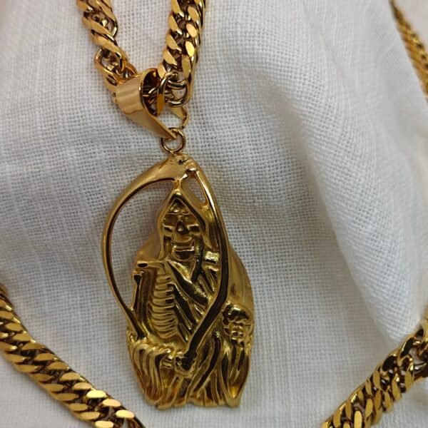 Gold stainless steel skeleton pendant necklace with a thick curb chain displayed on a brown box and white fabric.