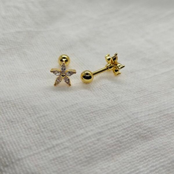 Gold-plated stainless steel flower screw back earrings with cubic zirconia stones on white fabric background