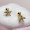 Gold-plated stainless steel flower screw back earrings with cubic zirconia stones on white fabric background
