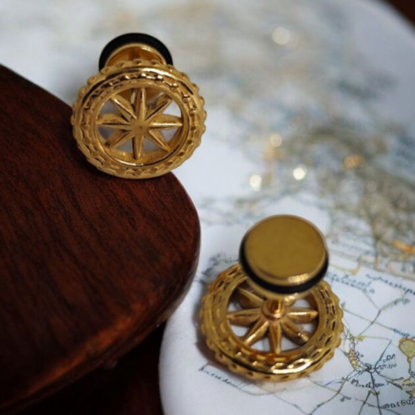 “Golden compass wheel cufflinks in stainless steel with gold finish on wooden and map background”