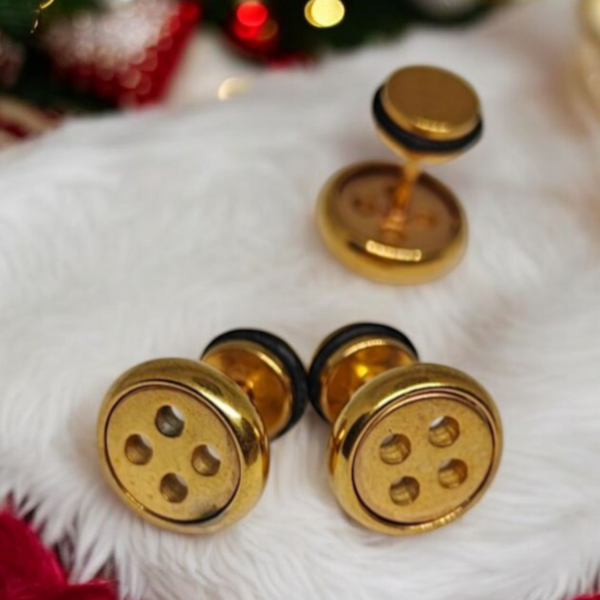 Gold plated stainless steel button screw back earrings on white and red fabric with festive lights in background