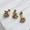 Cross shaped Gold-plated stainless steel screw-back earrings with a small beaded cluster design on white fabric.