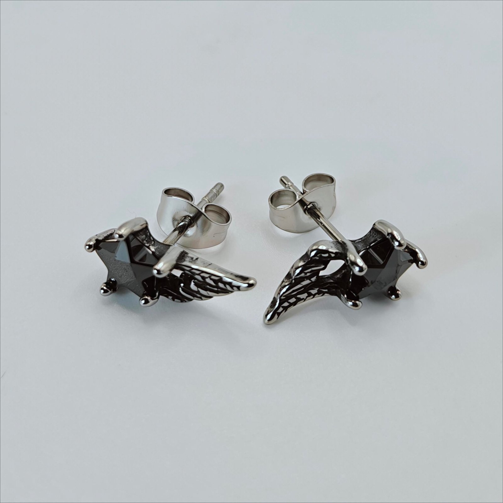 Black star-shaped zircon stud earring with detailed silver-tone wing