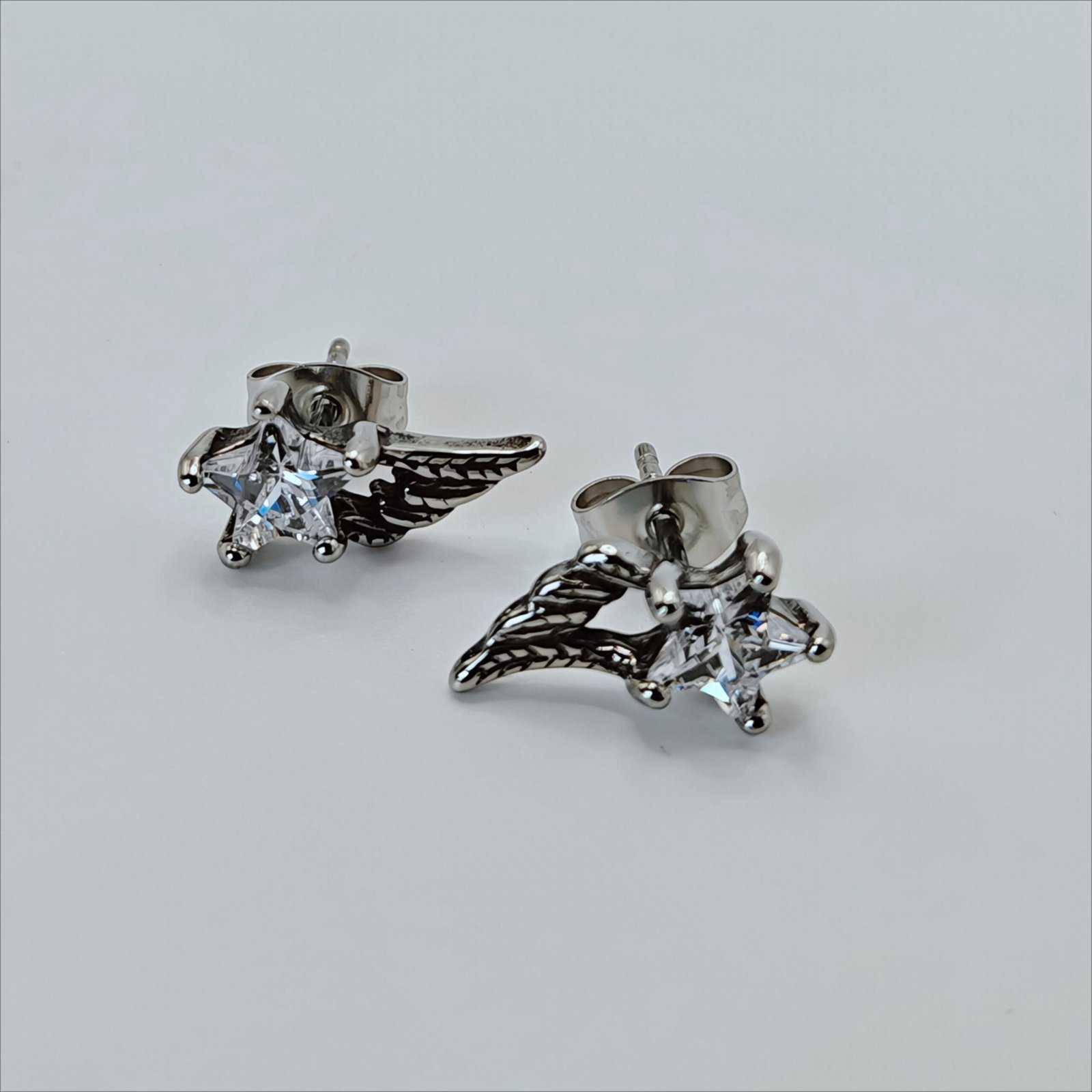 Clear star-shaped zircon stud earring with ornate feathered wing