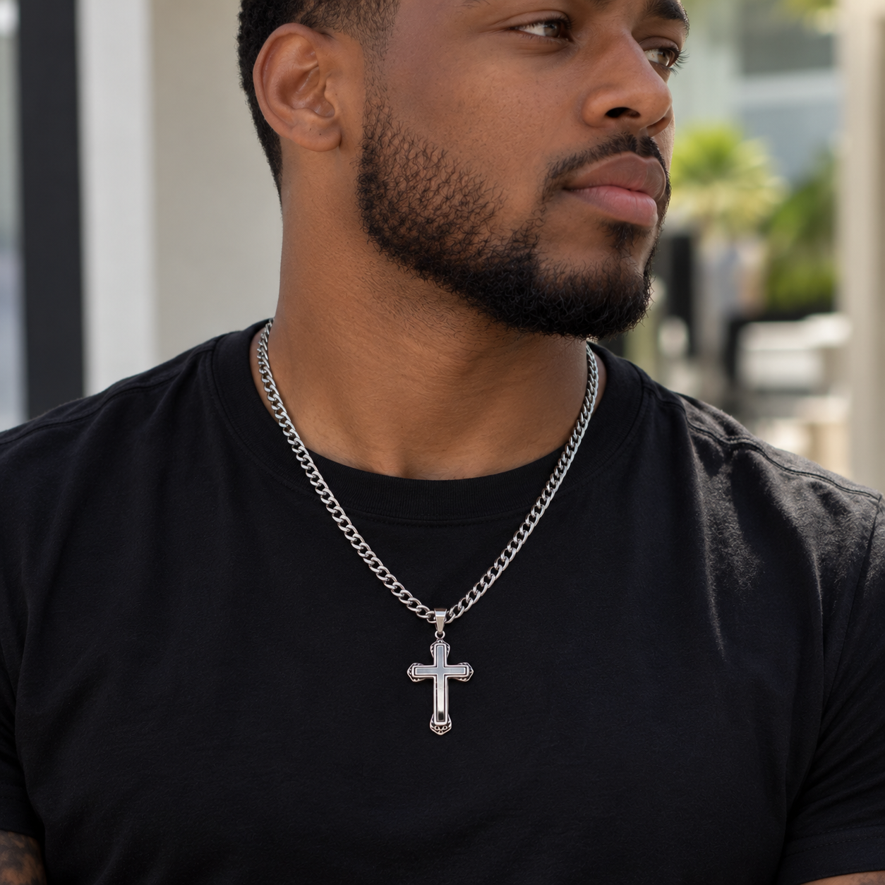 Man wearing silver cross pendant necklace with Cuban link chain